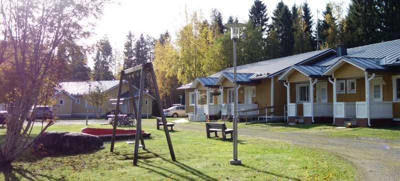 Keltaisen rivitalon edessä lasten leikkipaikka.